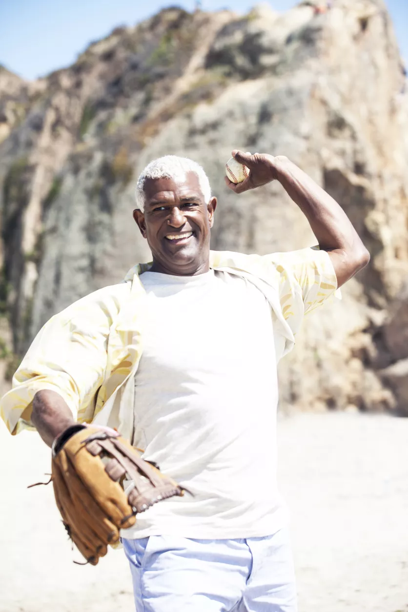 Senior man with a healthy rotator cuff throwing a baseball on the beach