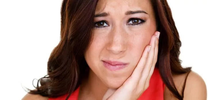 Closeup of a woman holding her swollen jaw for a TMJ and TMD concept