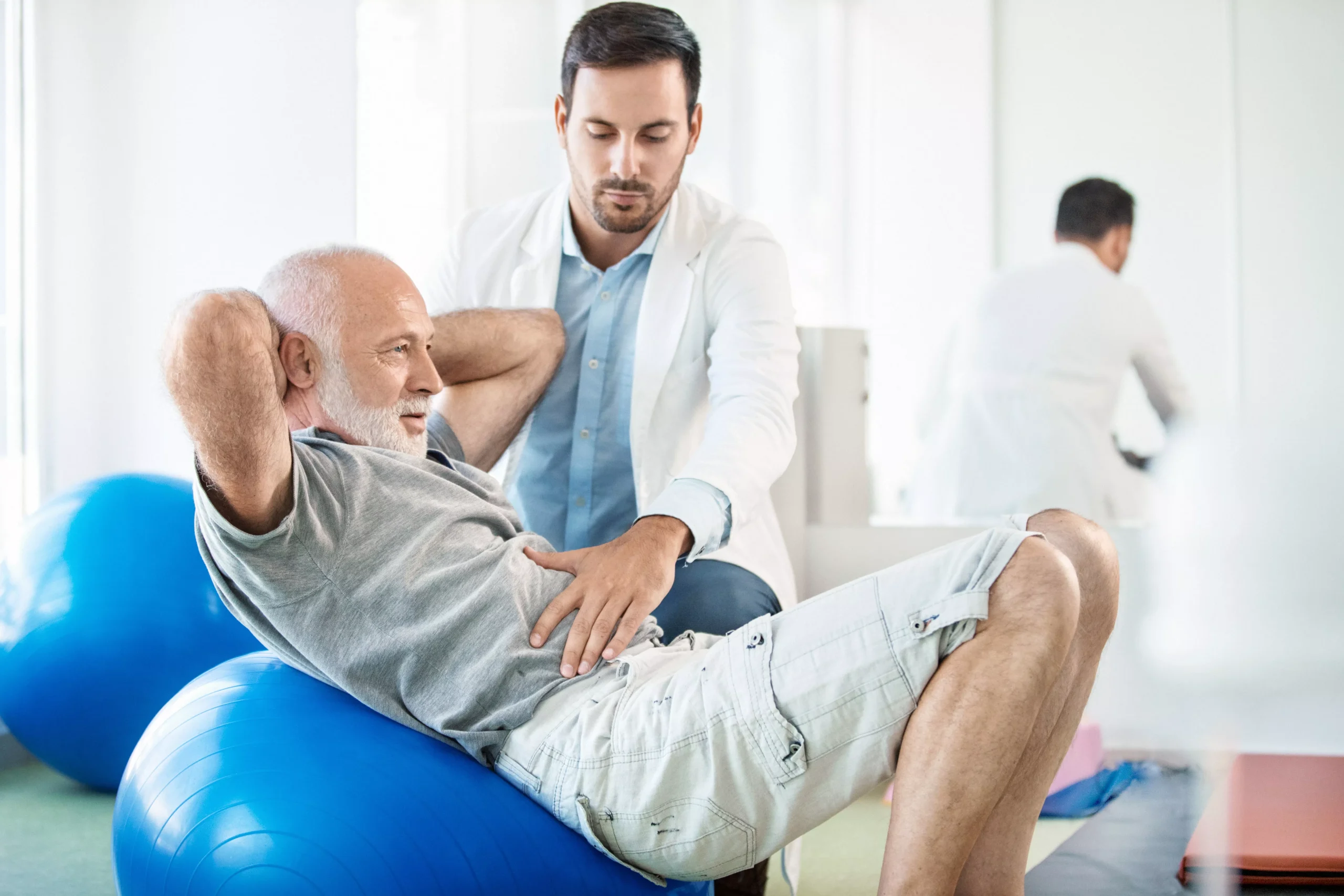 Closeup side view of a senior man having physical therapy for his sciatica with an expert doctor