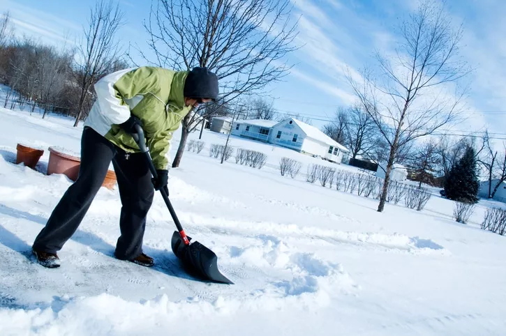 Woman shoveling the driveway after a winter snow. winter injuries concept