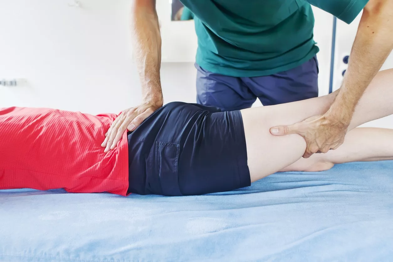 Physical therapist with a patient laying on table with sciatica nerve pain in lower back buttocks and leg