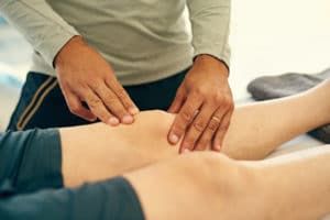 physical therapist using the Graston Technique to massaging his patient's knee