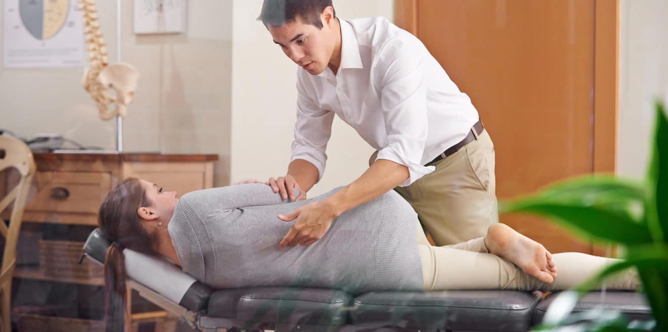 Shot of a chiropractor adjusting a young woman's spine