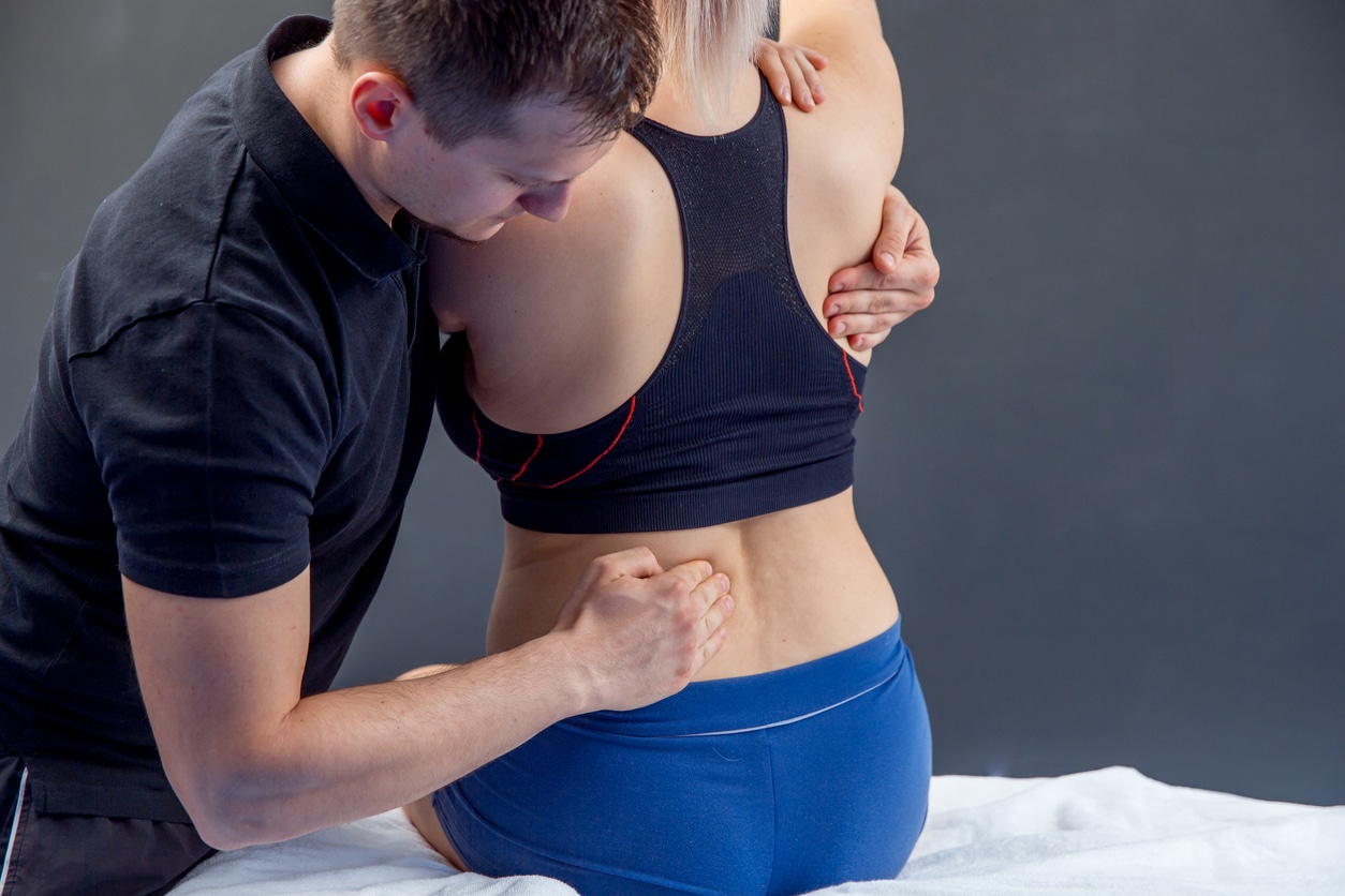 Physical Therapist Checking Woman's Back for lower back pain from poor posture