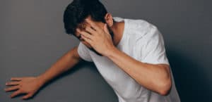 Man suffering from dizziness with difficulty standing up while leaning on wall. BPPV concept