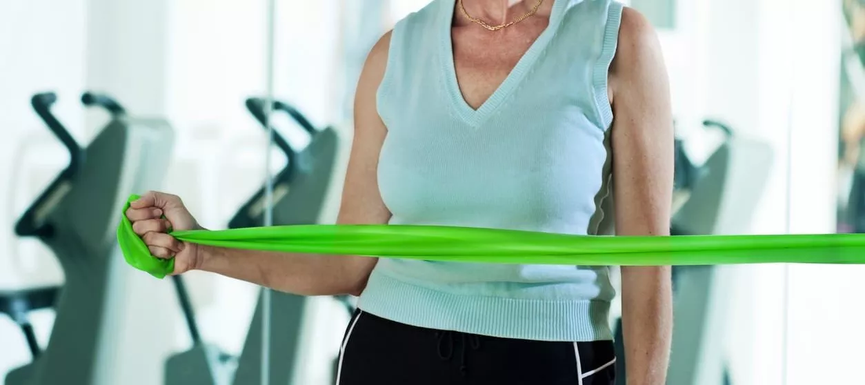 Woman doing internal and external rotator cuff exercises for shoulder injuries using a thera-band. This exercise is done to help recover from rotator cuff injuries. Horizontal shot.