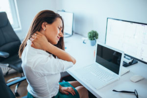 Young Businesswoman Suffering From Neck pain at an office desk