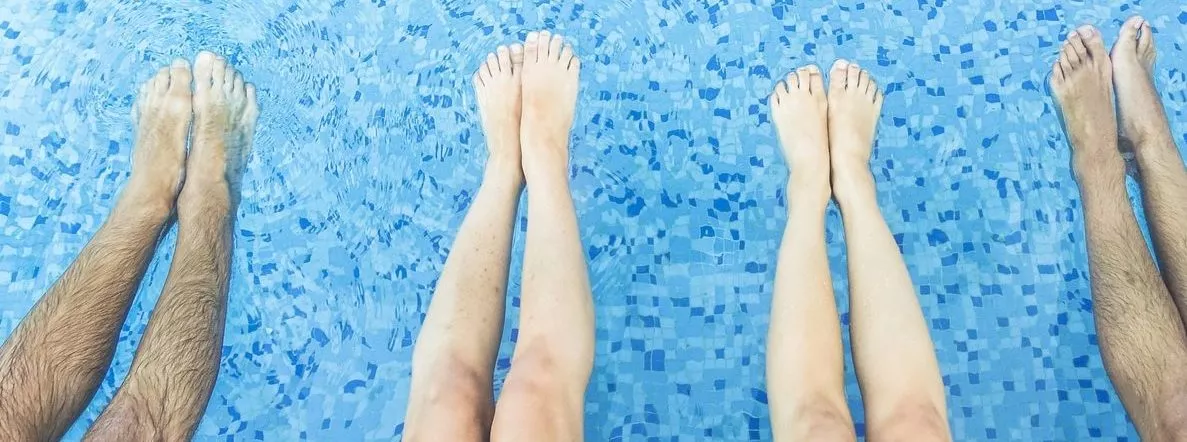 Legs view of friends relaxing and chilling in swimming pool showing different lengths in legs that may cause back pain