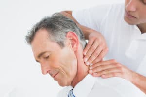 Physical therapist assisting with a man's neck
