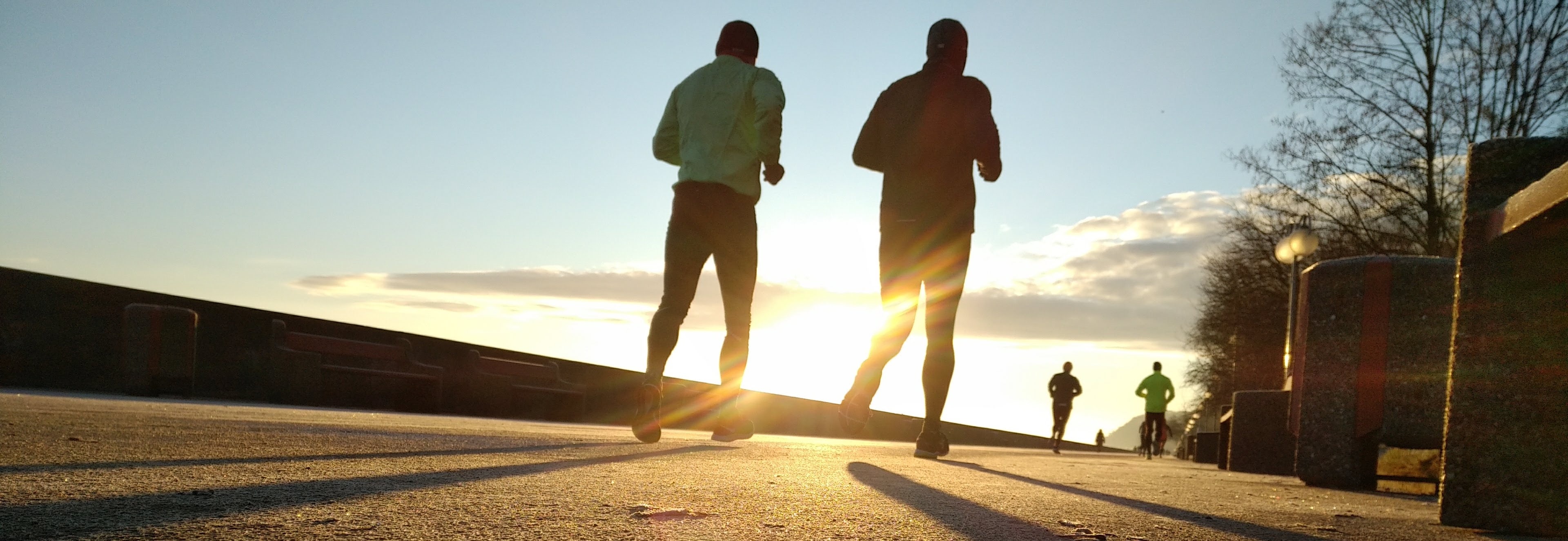 Two senior men running early in the morning sunrise in background
