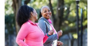 Two mature women power walking outdoors and smiling. Good exercise to make your workouts more intense.