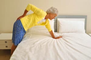 Woman leaning on her bed with back pain