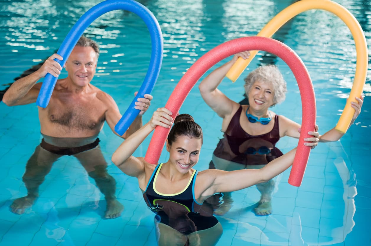 physical therapist with two seniors in an aquatic therapy class