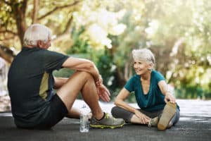 Senior couple outside doing warm-up exercises to prevent tendon injuries - concept of preventing tendonitis and tendinopathy.