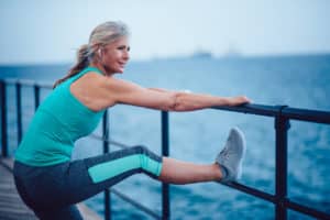 Senior woman doing warm-up exercises outside before her workout to avoid sprain or strain.