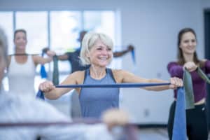 Adult woman having TheraBand exercises at a fitness gym to relieve pain coming from her bad shoulders.