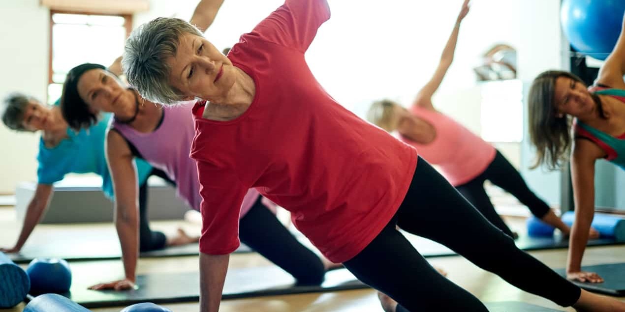 Group of adult women in a fitness gym performing aerobic exercises to help relieve signs and symptoms of concussion.