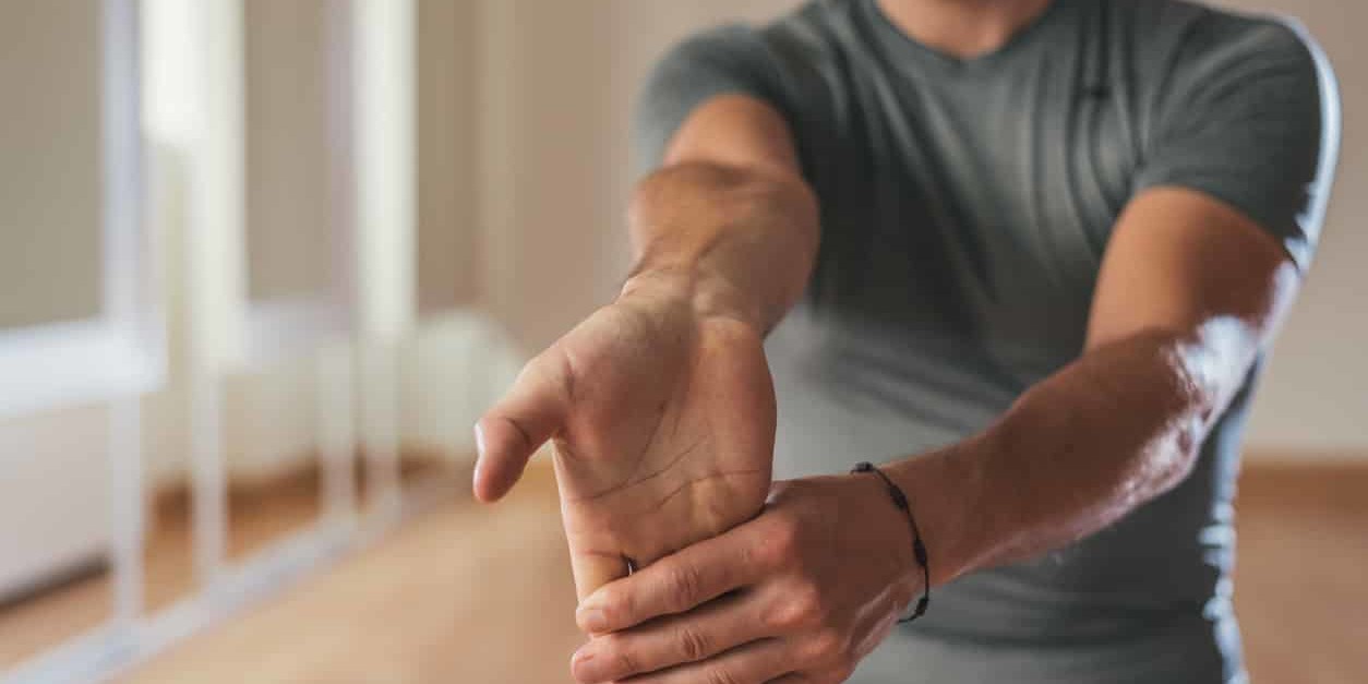 Man in a gym stretching forearm and hands to treat his carpal tunnel syndrome.