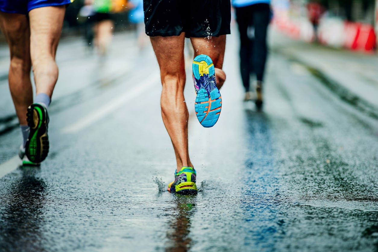 Group of people running outside in the rain - showing an idea of causes of plantar fasciitis.