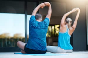 Mature couple at home doing stretching exercises to combat and relieve lower back pain.