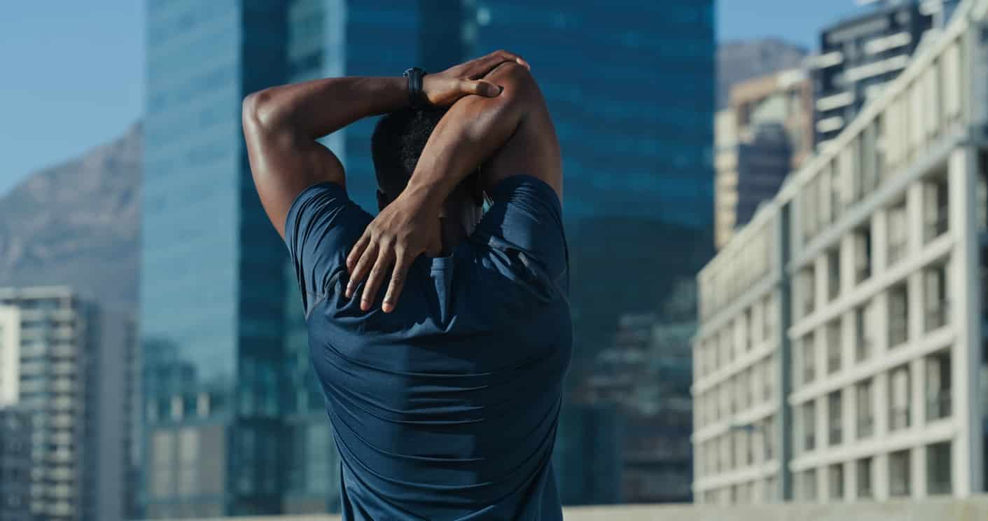 Mature man doing shoulder stretching exercises outside - preventing shoulder pain and tightness.