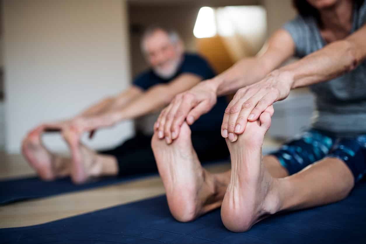 Senior couple at home doing foot exercises on the floor to help with their high ankle sprain.