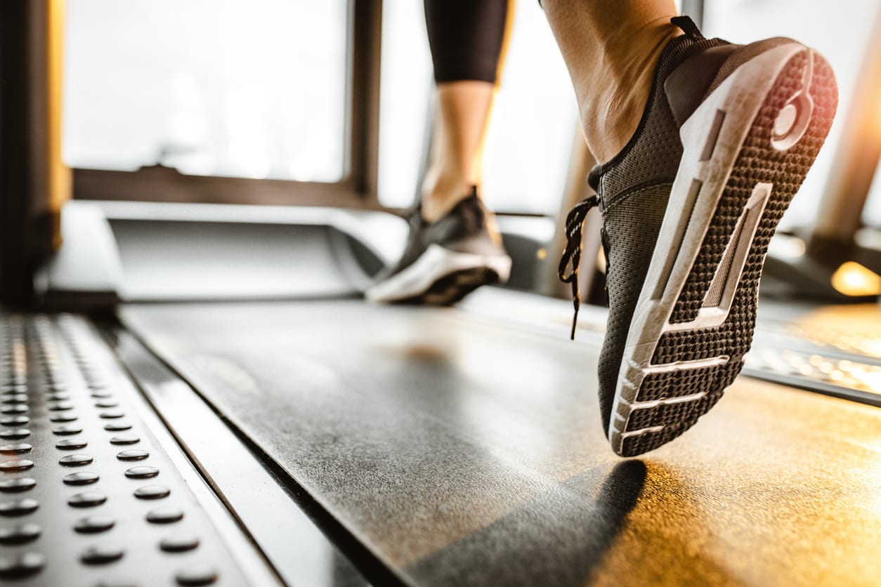 Woman running on a treadmill in a gym - relieving pain caused by ankle sprains.