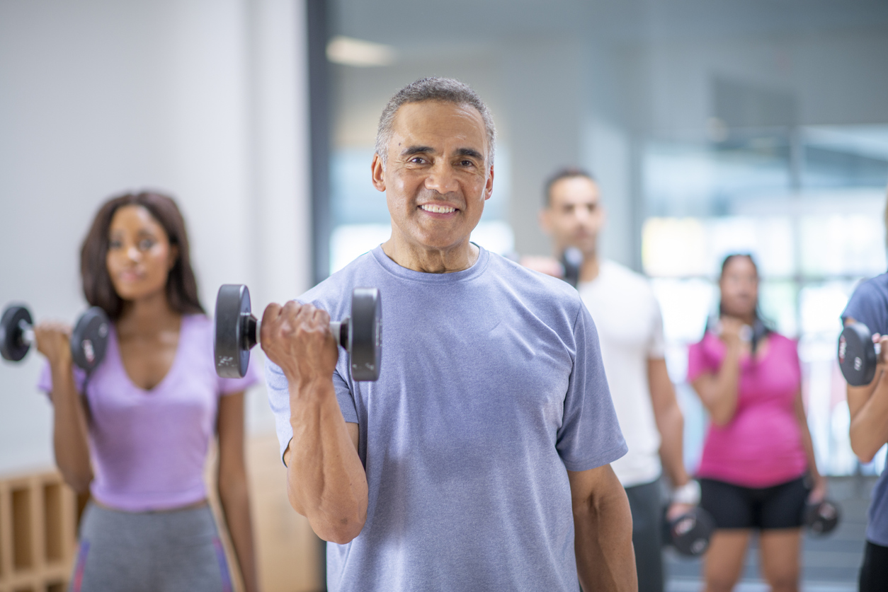 Senior man in a group fitness class - working out properly to avoid muscle strains.