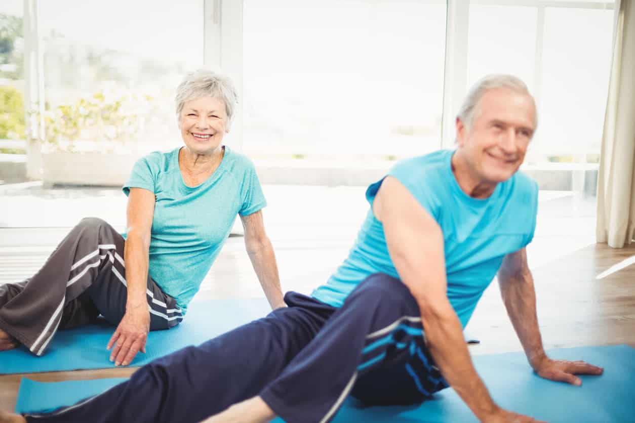 Senior couple doing core and lower back exercises to help alleviate the pain caused by Ankylosing Spondylitis.