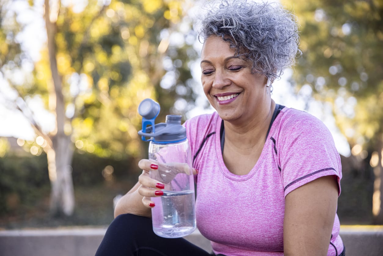 Adult woman drinking water while working out - preventing muscle spasms.