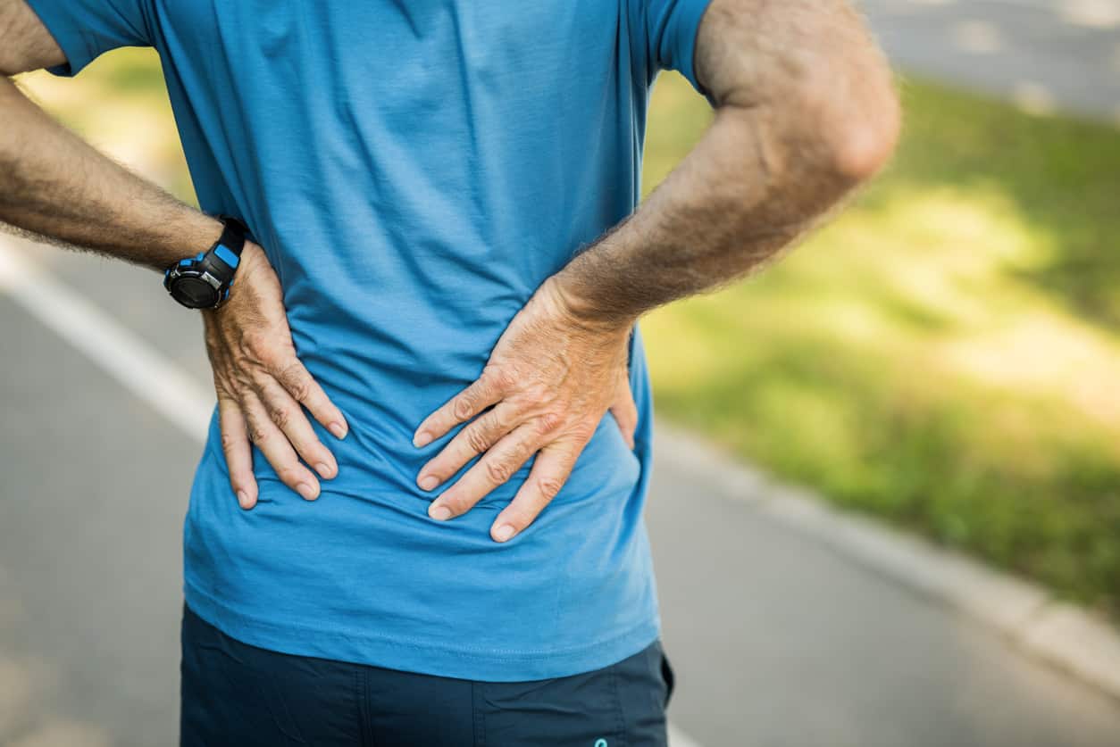 Senior man suffering from lower back pain - performing strengthening and stretching exercises.